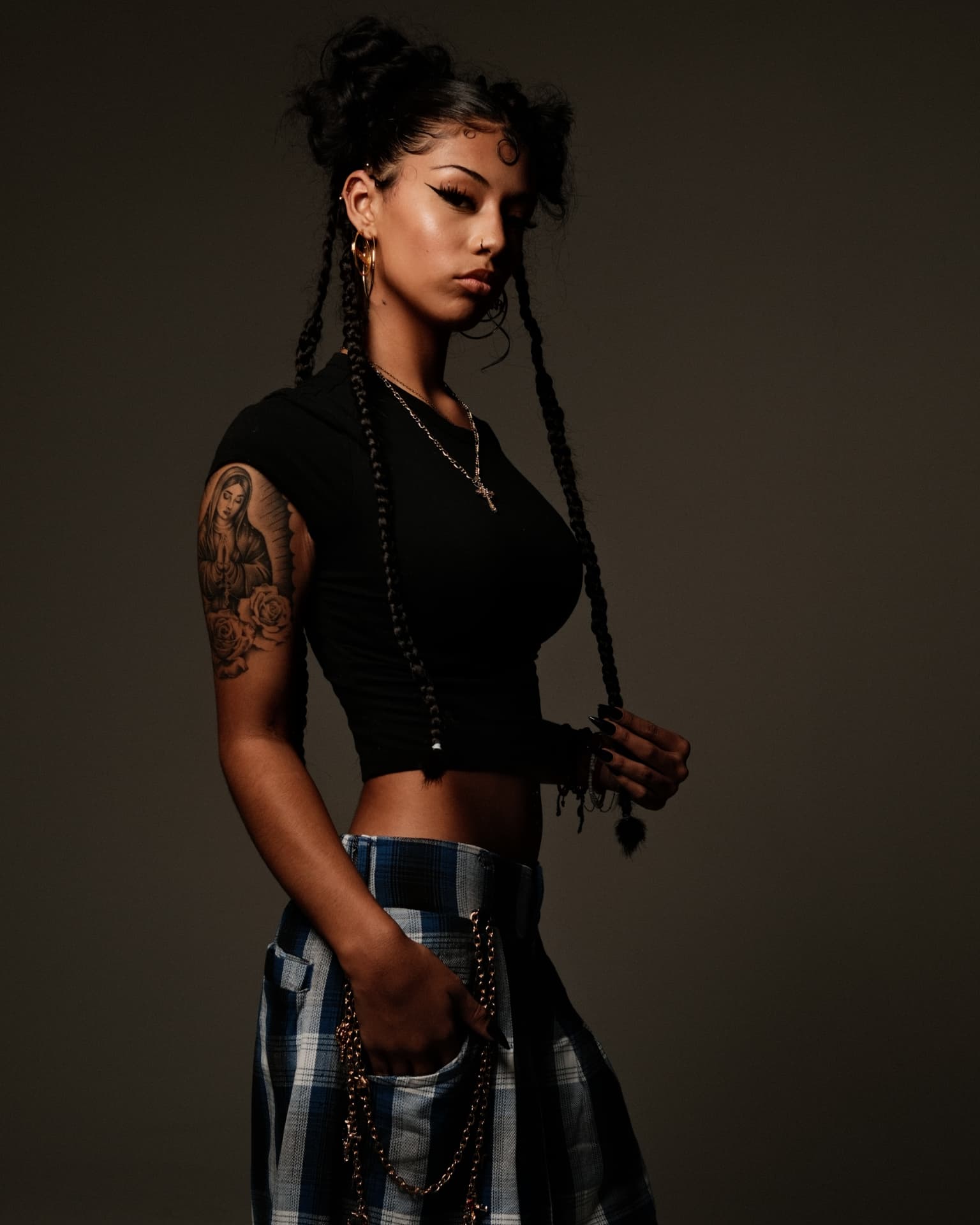 Studio portrait with long braids against a deep grey backdrop